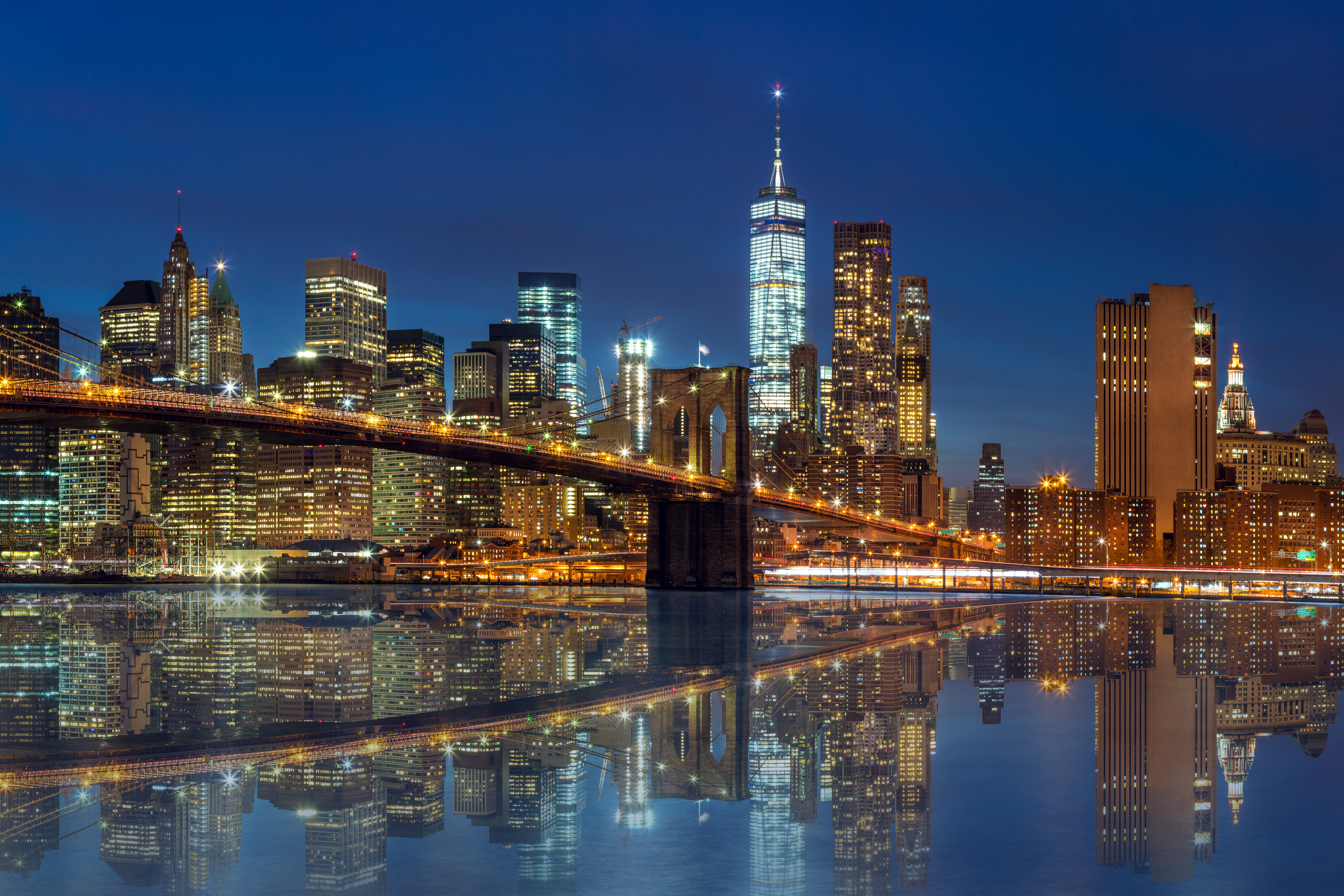 New York -  Manhattan Skyline with skyscrapers  and famous Brooklin Bridge by night with reflection